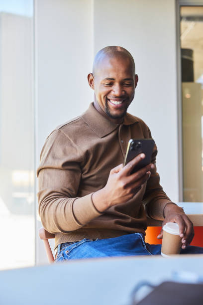 istock Young businessman smiling at a phone text during an office coffee break 2040541463