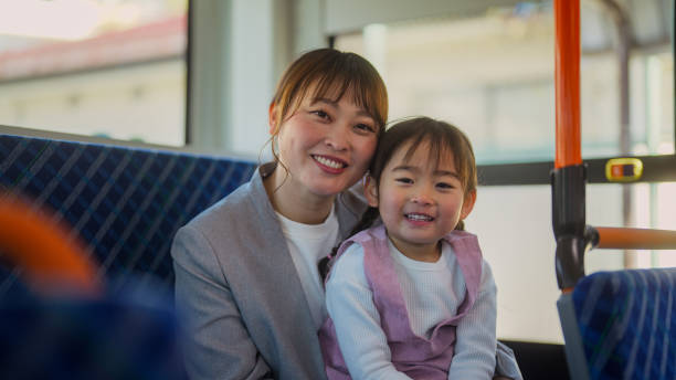 portrait of businesswoman commuting by bus with her small daughter - public transportation winter bus front view fotografías e imágenes de stock