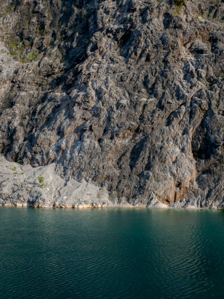 istock Beautiful rock mountain texture and blue water lake background, vertical style. Strong cliff with green peace water sea, natural travel scenery. Old quarry in Phang Nga Province, Thailand. 2040553319