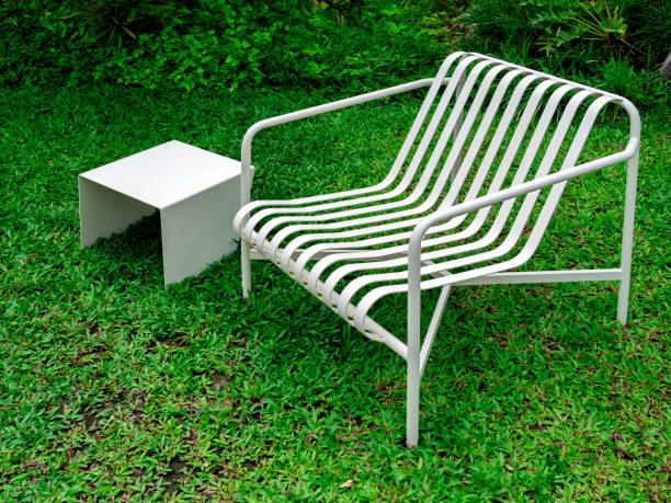 istock Empty modern minimal design of white empty curved armchair seat and small square side table, iron materials, decoration on green grass background at the summer outdoor backyard garden with nobody. 2040553635