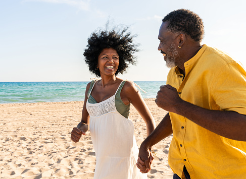 Beautiful mature black couple of lovers dating at the seaside - Married african middle-aged couple bonding and having fun outdoors, concepts about relationship, lifestyle and quality of life