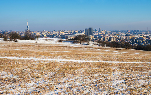 Wide snowy meadow and building and tower in Prague, Czech republic. Winter day.
