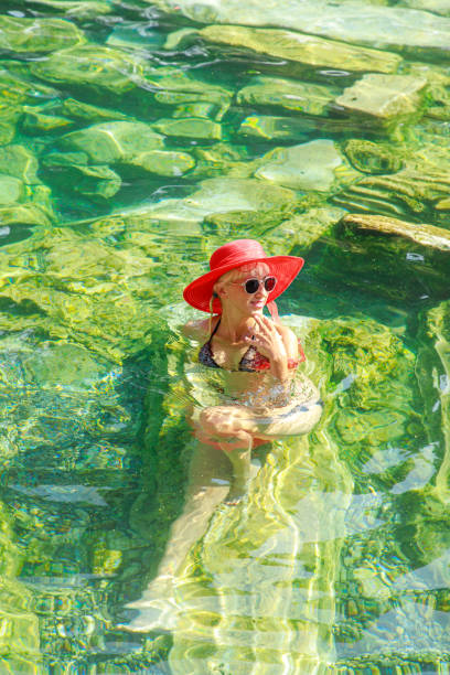 A young woman swims in a lake during the summertime.