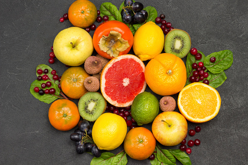 Set of varied, multicolored exotic fruits. Tangerines and oranges, kiwi and pear, persimmon and lychee. Black Background. Flat lay