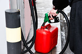 A man pouring fuel into a canister at a gas station.