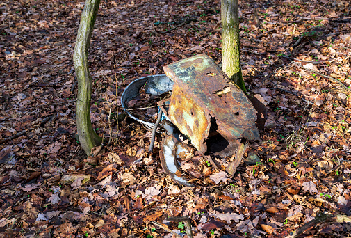 Metal waste on the ground in the autumn forest. Sunny weather.