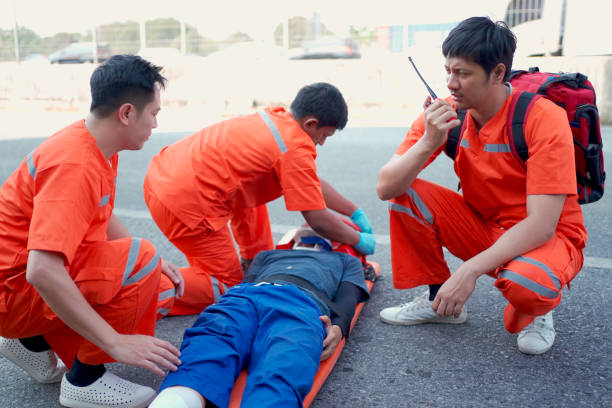 Emergency medical service team is rescuing Asian young man The emergency response team is trying to administer first aid to an Asian man who has had an accident on the side of the road.