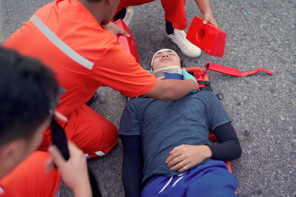 Emergency medical service team is rescuing Asian young man The emergency response team is trying to administer first aid to an Asian man who has had an accident on the side of the road.