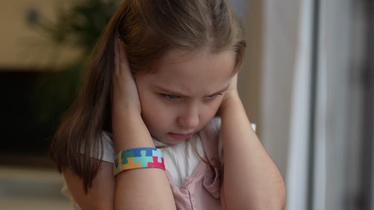 Child girl with autism covering her ear with her hands noise