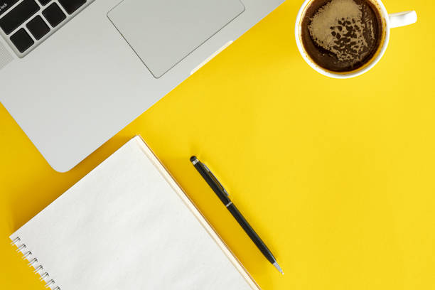 istock Cup of coffee, notepad and laptop on yellow background, flat lay. 2040636434