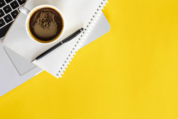 istock Cup of coffee, notepad and laptop on yellow background, flat lay. 2040636449