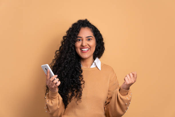 istock woman smiling and holding mobile phone 2040644485