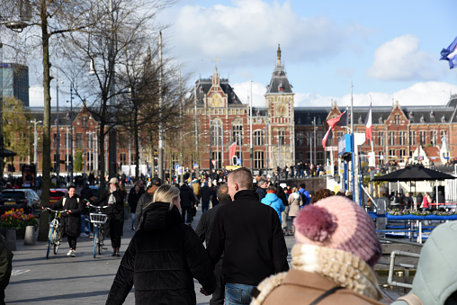 Amsterdam City during King's Day (Koningsdag) with several pedestrians next to Amsterdam Centraal. The image was captured during spring season.