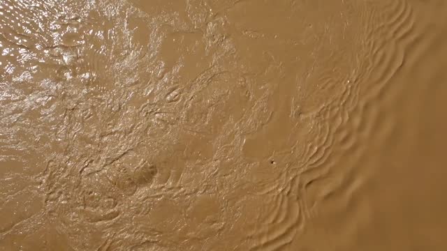 top view of strong current of muddy and turbulent river flowing down