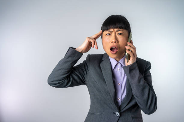 Worried businessman talking on the smart phone standing near big window in office.