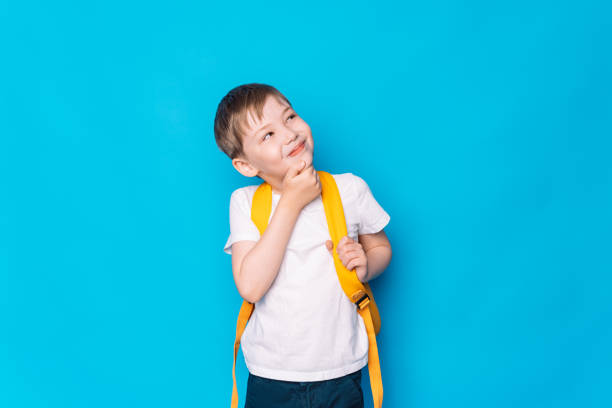 Boy with a yellow backpack thought in front of a blue background.