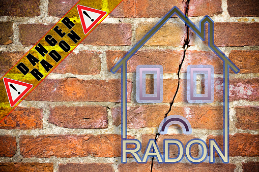 The danger of radon gas in our homes - concept image with an outline of a small house with radon text against a cracked brick wall