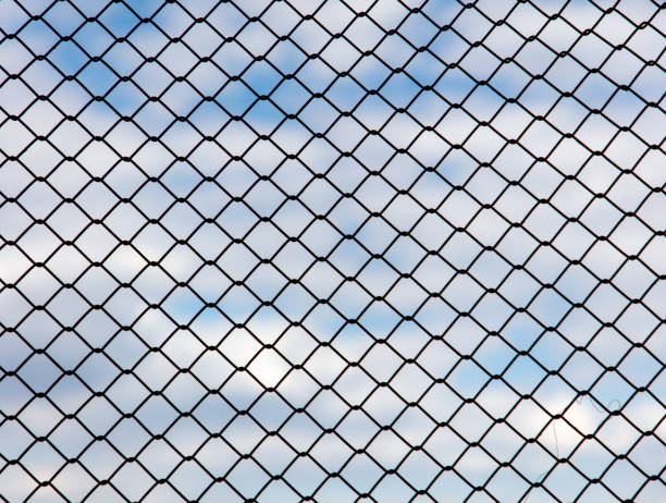 istock Chain link fence against the blue sky and clouds. Abstract background 2040708141