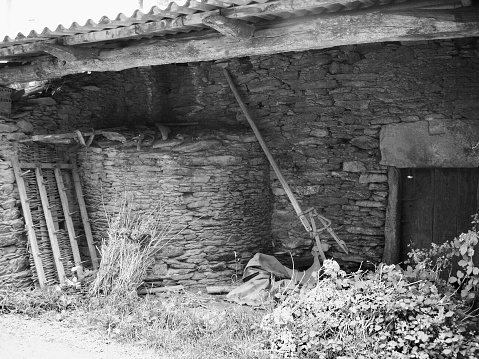 Agricultural equipment, weed in old stone barn. Camino de Santiago, Galicia, Spain.