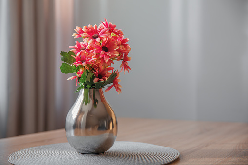 Vase with a bouquet of flowers on the background of the gray wall