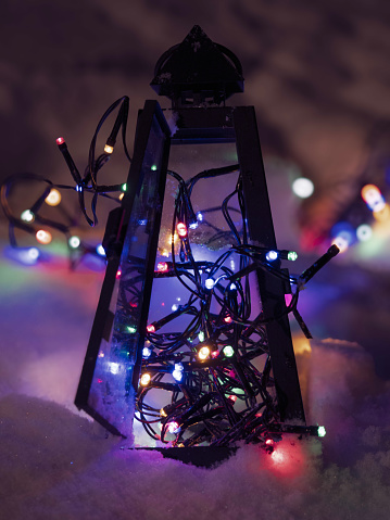 Snow-covered ground under a lantern adorned with multiple glowing lights