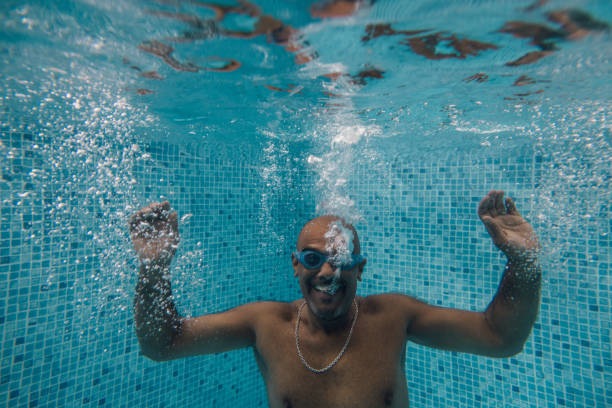 istock Mature Man Holding Arms Up Underwater 2040743323