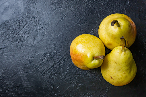 Fresh fruit on dark background. Composition of three pears.