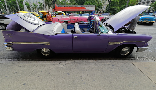 Havana, Cuba-October 07, 2019: Purplish blue old American classic car -almendron, yank tank- Dodge Kingsway Custom Convertible 1959 suffers some problems, engine at repair, Paseo del Prado promenade.