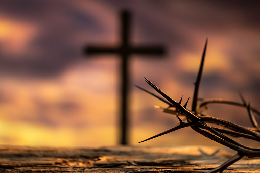 The holy cross of Jesus Christ on the grass with the strong light of the sunset sky symbolizes death and resurrection love.