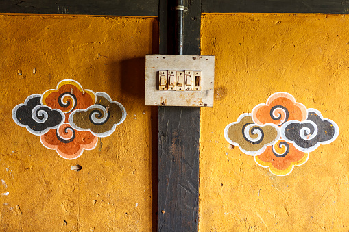 Old light switch on a wwall with Bhuddist decorations, Luentshe Dzong, Bhutan, Asia.