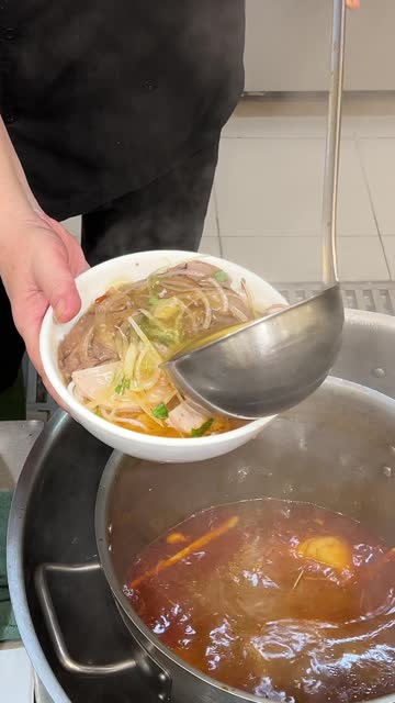 pour fa soup vietnam Hands pouring broth into bowls of pho