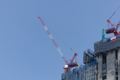 Cranes on a construction site against blue sky with blank copyspace