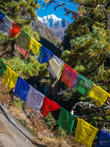 Colourful Buddhist prayer flags flying on the Mt Everest Base Camp trail framing the snow capped summit of Lhotse 8516m high in the Himalayan mountains of Nepal.