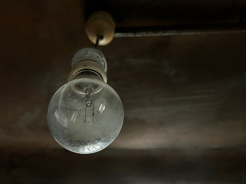 Old light bulb hanging on ceiling with copy space