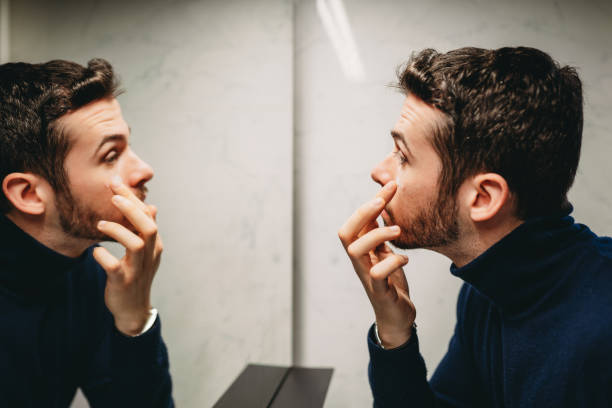 istock A young adult man is applying face cream at the mirror 2040802149