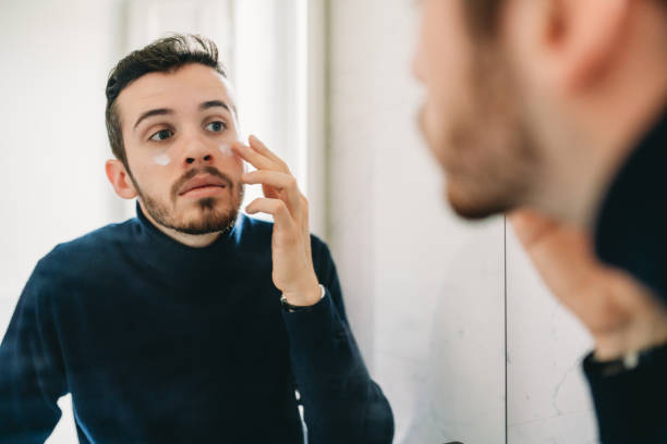 istock A young adult man is applying face cream at the mirror 2040802245
