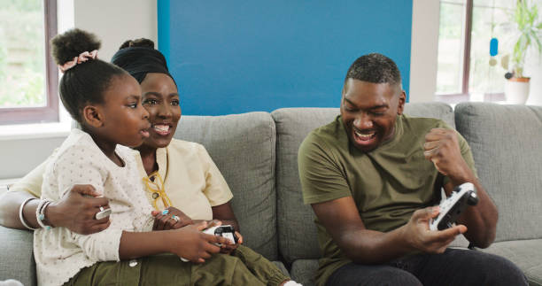 istock Black family, video game and win in living room sofa with virtual competition and controller at home. Happy, mother and dad with a young girl on a couch with kids gaming of mom, father and child 2040804925