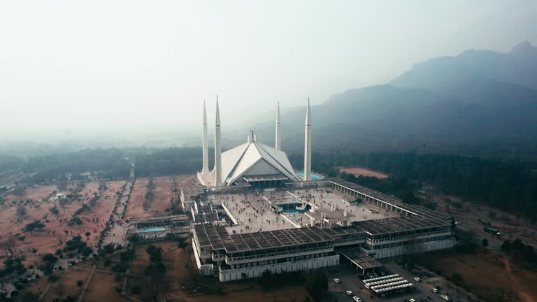 Faisal mosque in islamabad, tranquil morning with soft light, mountains in backdrop, aerial view