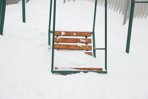 A children's swing, completely covered with snow.
