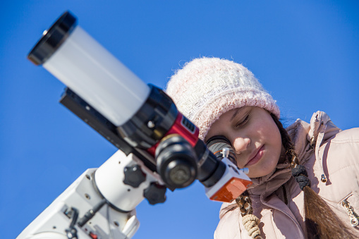 A girl watches the sun through a solar telescope.