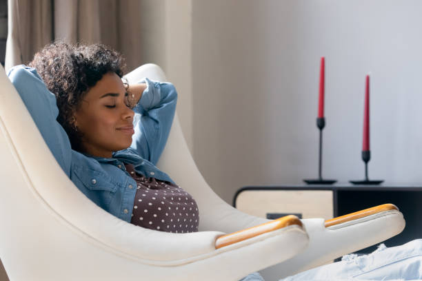 Peaceful young African American woman relaxing in comfortable armchair.