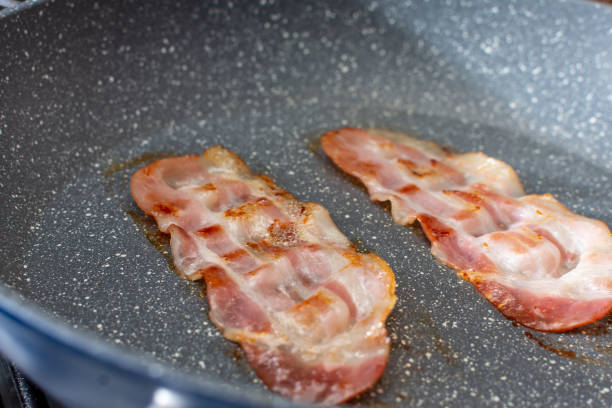 istock Two pieces of bacon are fried in a pan 2040886381