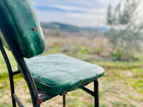 A green old chair in the garden. Although it is still colorful and looks new, the model shows that it is very old.