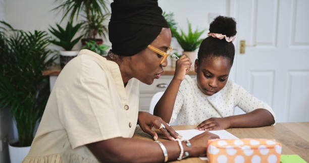 istock Black mother, kid and learning in home, teaching and studying together at table in homeschool. Mom, girl and education in house, homework help and reading knowledge on paper for child development 2040926353