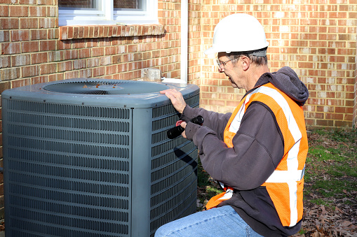 Home inspection of central air unit by a maintenance worker