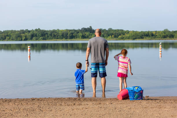 istock Father & Two Children In Shallow Water At Beach 2040953844