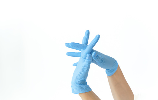 Two blue surgical medical gloves isolated on a white background with hands. Production of rubber gloves. A doctor or nurse, a cosmetologist puts on nitrile protective gloves