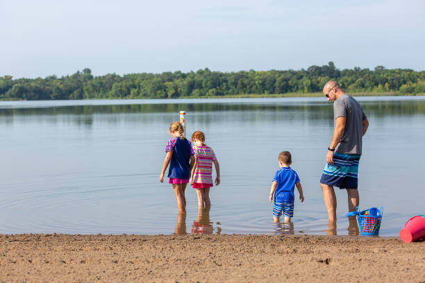 istock Father & Three Children In Shallow Water At Beach 2040954412