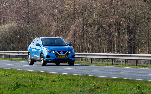 Netherlands, Overijssel, Twente, Wierden, March 19th 2023, side/front view close-up of a senior couple driving in a Dutch blue 2020 Nissan 2nd generation Qashqai SUV on the N36 at Wierden, the Qashqai is made by Japanese manufacturer Nissan Motor Co. Ltd. since 2006, the N36 is a 36 kilometer long highway from Wierden to Ommen