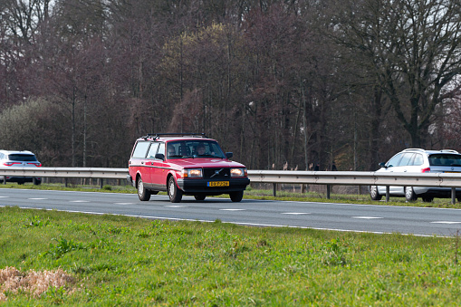 Netherlands, Overijssel, Twente, Wierden, March 19th 2023, side/front view close-up of a red 1992 Volvo 240 Polar station wagon driving on the N36 at Wierden, the 200-series was made by Swedish manufacturer Volvo from 1984-1993, the N36 is a 36 kilometer long highway from Wierden to Ommen